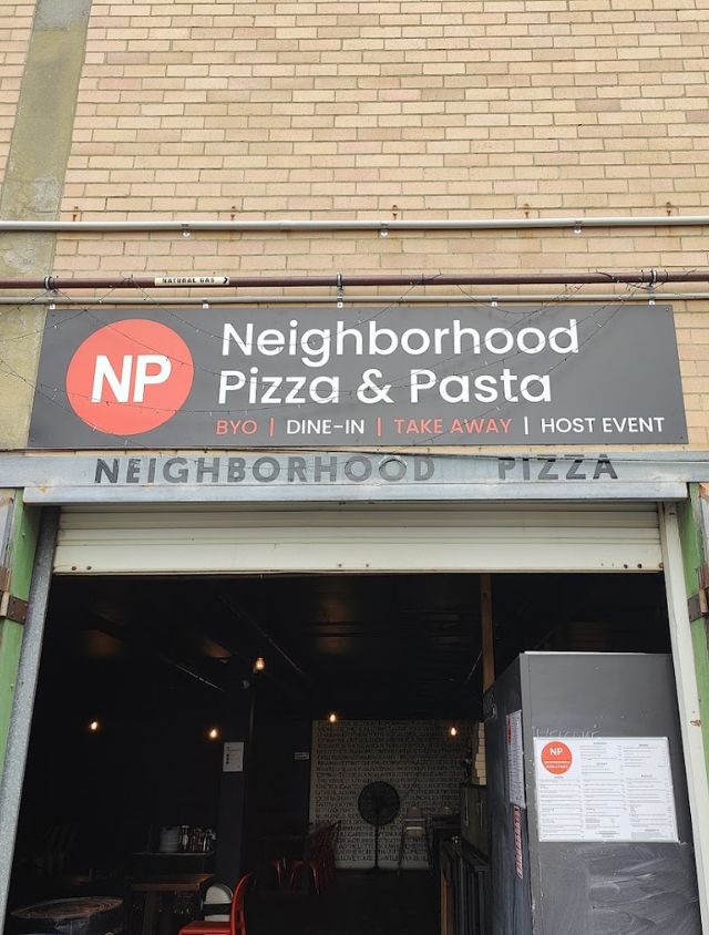 Storefront entrance of Neighborhood Pizza and Pasta in Mount Hawthorn, showing the red circle logo sign with BYO, dine in, take away and host event listed underneath.